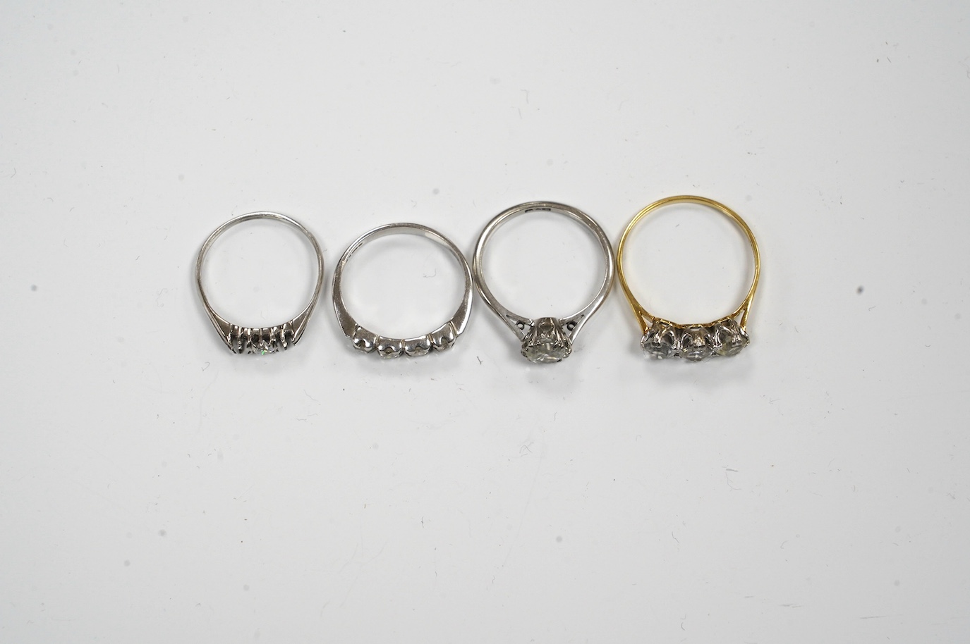 A 9ct gold and four stone diamond set ring, size L, a white metal and solitaire diamond ring and two simulated diamond rings. Condition - poor to fair